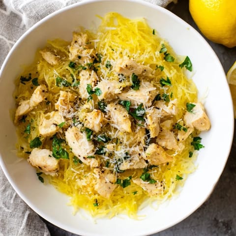 Savory lemon garlic chicken sizzling in a skillet with minced garlic and bright lemon zest, ready to serve over squash.