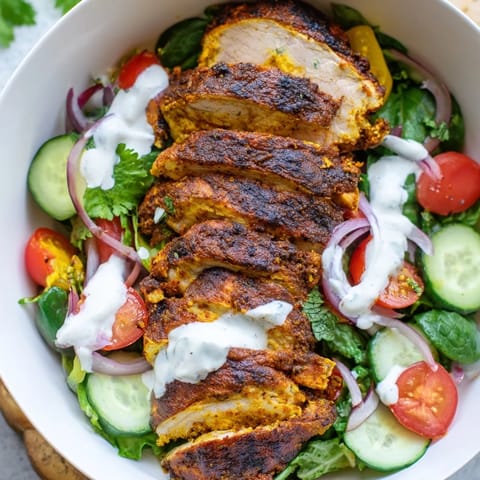 A vibrant chicken shawarma salad bowl with tender sliced meat, fresh herbs, and zesty garlic sauce on greens.  