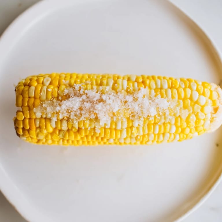 Steaming corn on the cob, sweet and juicy, served with butter and a dash of sea salt.