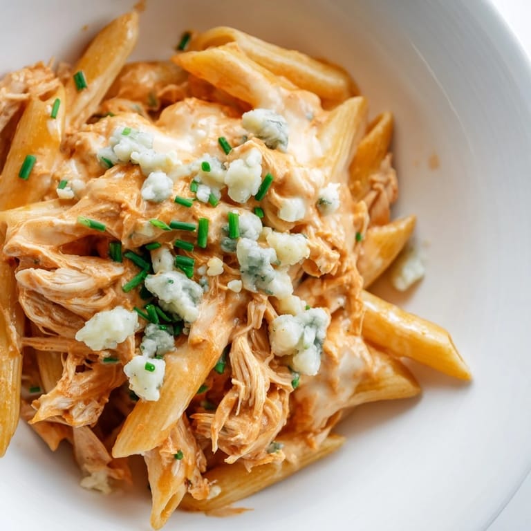Steaming bowls of Buffalo Chicken Pasta paired with celery sticks, highlighting the rich, cheesy texture and bold flavors of the main course.