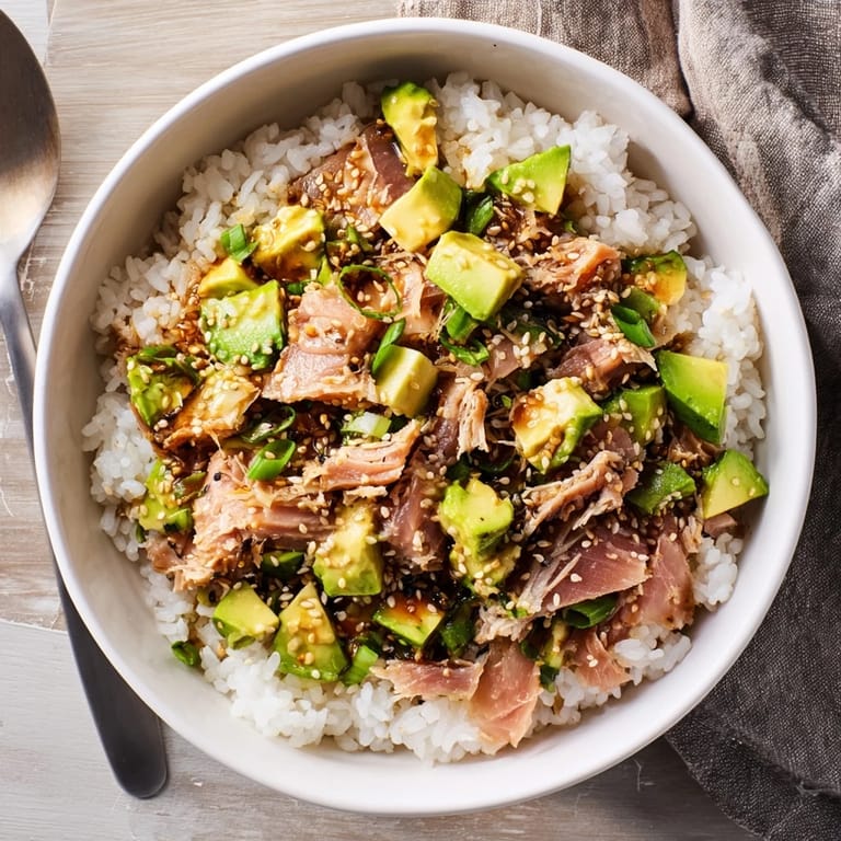 Healthy Tuna Avocado Rice Bowl served warm, garnished with scallions and toasted sesame seeds.