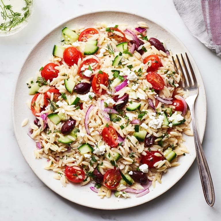 Healthy Greek Orzo Salad in a serving dish, showing diced cucumber, red onion, and Kalamata olives glistening with dressing.