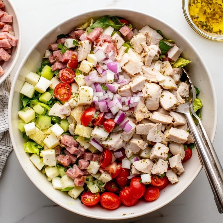Plated Italian Deli Chopped Chicken Salad garnished with fresh herbs, served with Italian bread on a rustic wooden table.